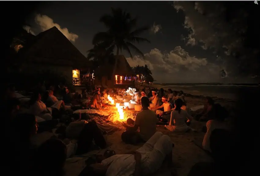 People meditating by a fire in the beach